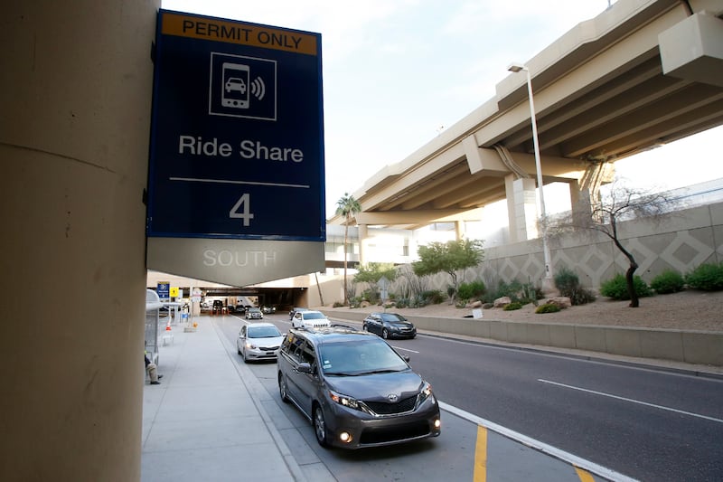 In this Dec. 18, 2019, file photo passengers find their rides at the Ride Share point as they exit Phoenix Sky Harbor International Airport in Phoenix.