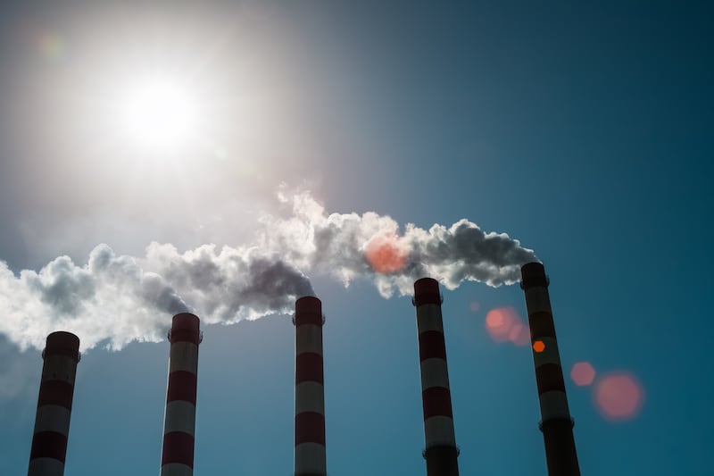 A line of smokestacks are framed against the sky.