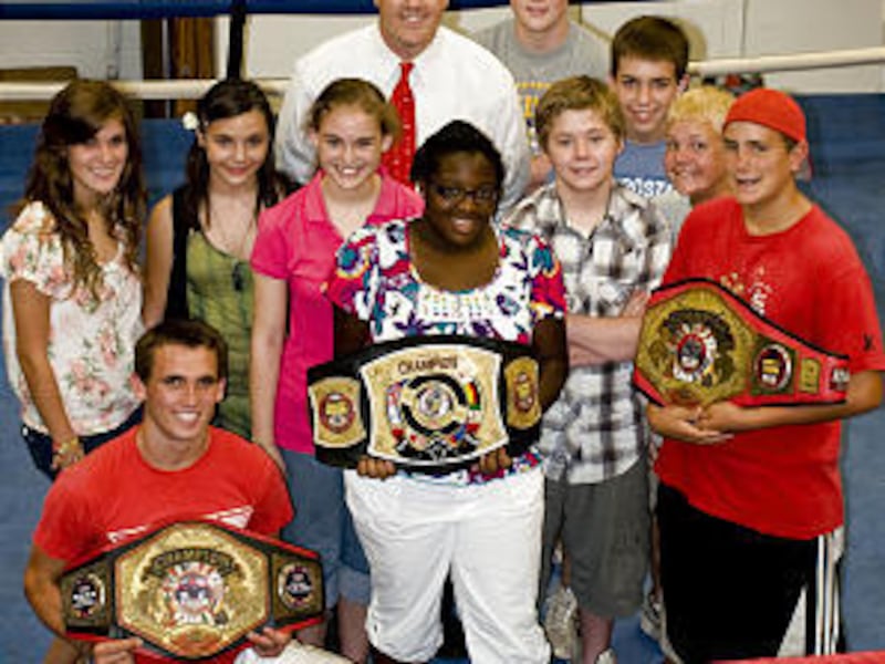 Bishop Rainey Rogers shows his boxing championship belts to youths from his ward.
