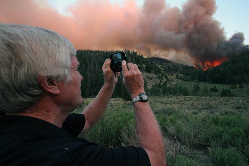 George Robinson, who lost his cabin in the Church Camp Fire, uses his camera phone to take a picture as flames spread Tuesday, June 26, 2012, from Argyle Canyon to Indian Canyon in Duchesne County. The fire has burned 4,000 acres since Sunday, June 24, 20