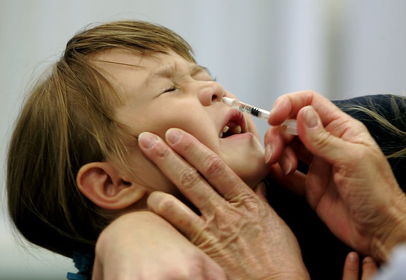 A child reacts as she is given a FluMist influenza vaccination.