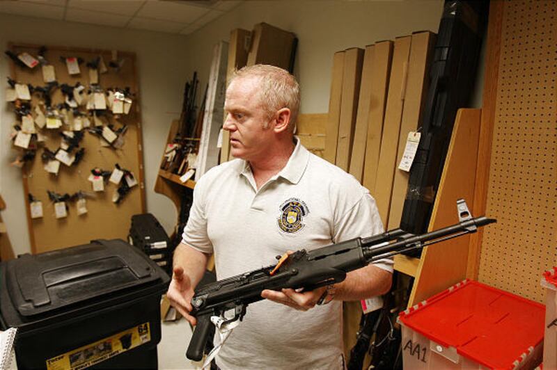 Tom Mangan, a spokesman for the U.S. Bureau of Alcohol, Tobacco, Firearms and Explosives, holds an AK-47 style rifle in the evidence locker at the local ATF offices Friday, Nov. 21, 2008 in Phoenix. The AK-47 rifle with folding stock is a favorite weapon
