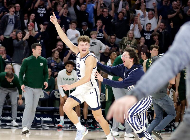 A Utah State fan runs onto the court to celebrate Aggies’ win over No. 13 Colorado State with freshman guard Mason Falslev.