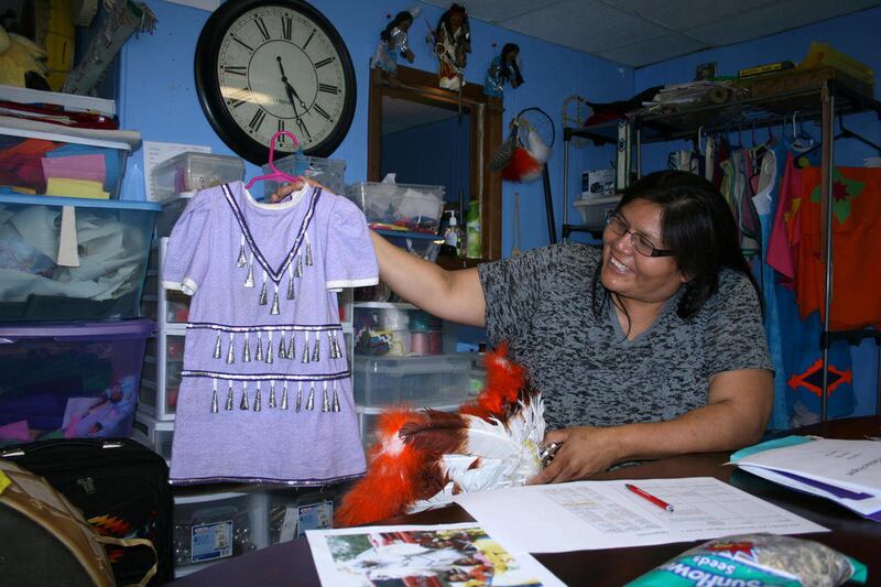 In this July 19, 2012 photo, Gale Spotted Tail, director of the Rosebud Sioux Tribe's Child Care Services program, shows off an outfit made through the program's Song and Dance Project in Rosebud, S.D. The Song and Dance Project aims to teach families how