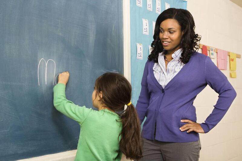A teacher observes as a student writes on a blackboard.A Newcastle University professor in England said the growth of technology makes teaching conventional spelling and grammar a "bit unnecessary."