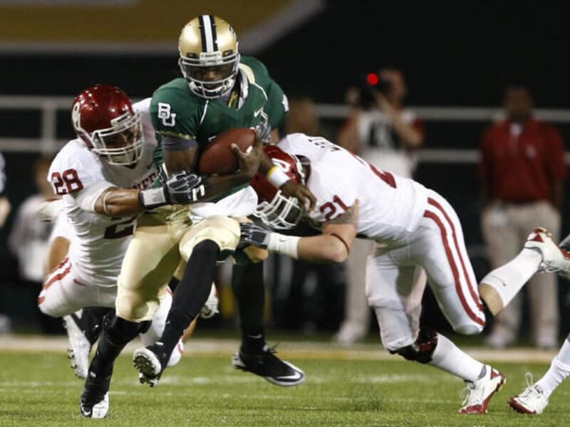 Baylor quarterback Robert Griffin, center, is brought down by Oklahoma defenders Travis Lewis (28) and Tom Wort (21) on a run in the first half of an NCAA college football game.
