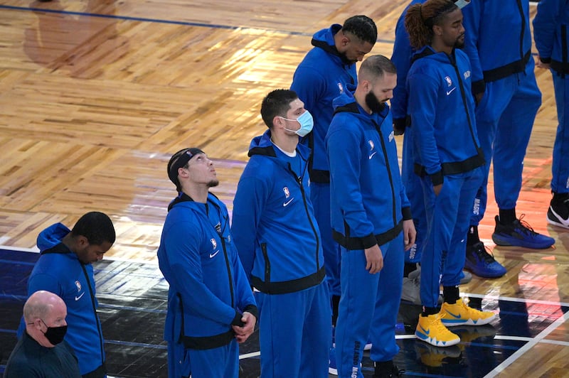 Orlando Magic head coach Steve Clifford, left, and center Nikola Vucevic, center, wear face masks to help prevent the spread of COVID-19 during the singing of the national anthem before an NBA basketball game against the Sacramento Kings, Wednesday, Jan. 27, 2021, in Orlando, Fl