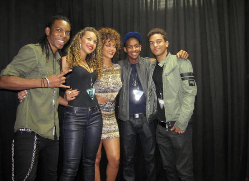In this Aug. 5, 2011 image made available by wearecoverdrive.com Rihanna poses for a photograph with her supporting act Cover Drive, from left, Barry Hill, Amanda Reifer, Rihanna, T. Ray Armstrong and Jamar Harding backstage at Kensington Oval, near Bridg
