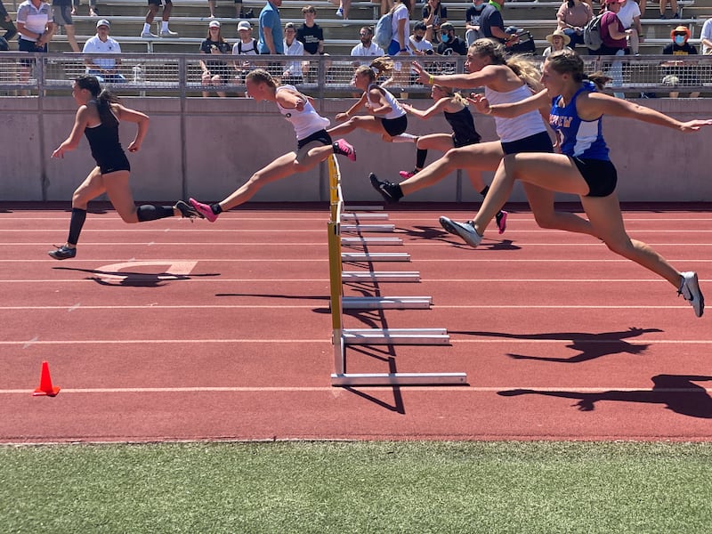 Athletes compete in the 100-meter hurdles at the 5A state meet at Davis High School.