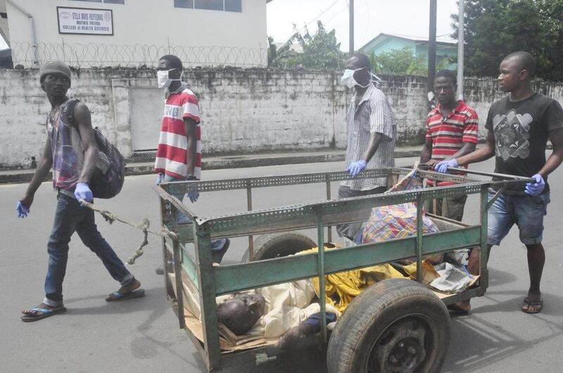 Volunteers push cart with a man suspected of having Ebola virus, to a health centre in central area Monrovia, Liberia, Sunday, Oct. 5, 2014.