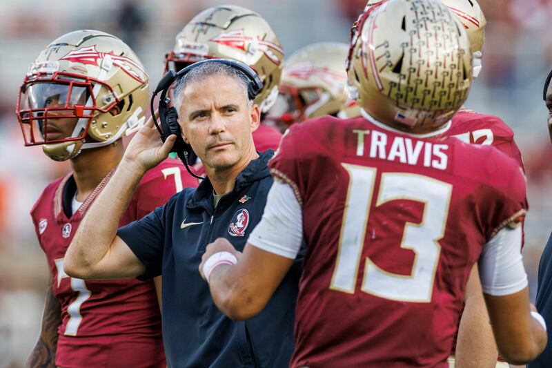 Florida State coach Mike Norvell listens to quarterback Jordan Travis during a game against Miami on Nov. 11, 2023.