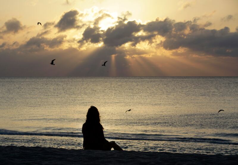 A woman meditates on the beach in Miami Beach, Fla.