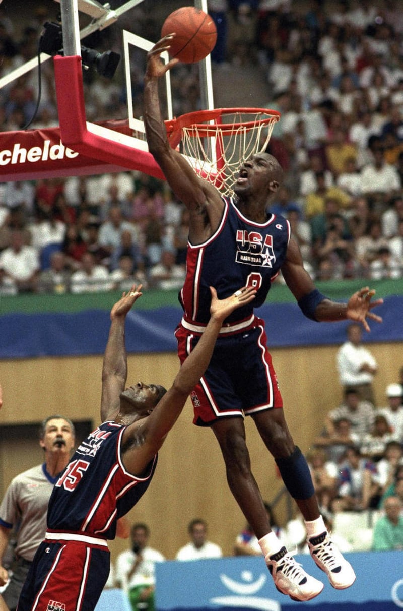 In this July 27, 1992, file photo, USA’s Michael Jordan sails high above teammate Magic Johnson knocking away a shot during the first half of their preliminary round basketball game with Croatia at the Summer Olympics in Barcelona.
