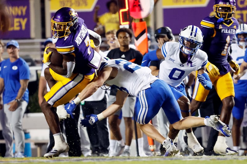 East Carolina running back London Montgomery, left, takes a hit from BYU's Tanner Wall, front right, with BYU's Evan Johnson (0) looking on during game in Greenville, N.C., Saturday, Sept. 20, 2025.