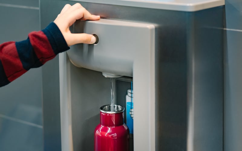 Hand pressing the button of a drinking water filling station.