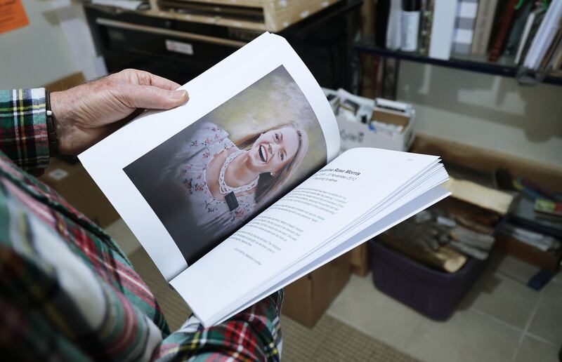 Utah artist JR Johansen looks through a published book of portraits of deceased Latter-day Saint missionaries.