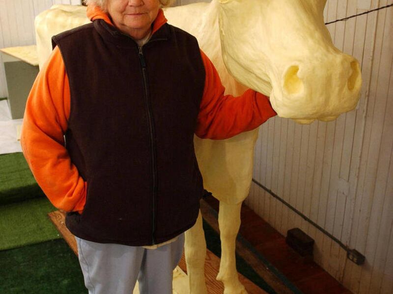 FILE - In this Aug. 6, 2003, file photo Norma "Duffy" Lyon stands next to a life-size dairy cow she sculpted from butter at the Iowa State Fair in Des Moines, Iowa. Lyon, who famously sculpted butter into cows, Elvis and even Jesus for the Iowa State Fai
