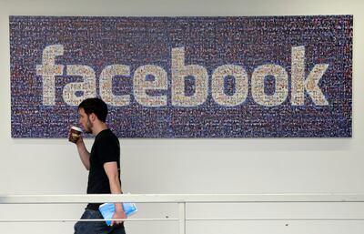 In this March 15, 2013, file photo, a man walks past a sign at Facebook headquarters in Menlo Park, California. Facebook gave some companies more extensive access to users’ personal data than it has previously revealed, letting them read private messages