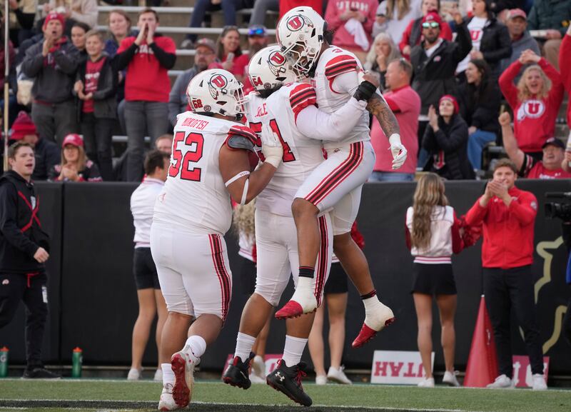 Utah quarterback Ja’Quinden Jackson, right, celebrates with offensive linemen Paul Maile, center, and Michael Mokofisi after running for a touchdown in the first half of an NCAA college football game against Colorado, Saturday, Nov. 26, 2022, in Boulder, Colo. (AP Photo/David Zalubowski)