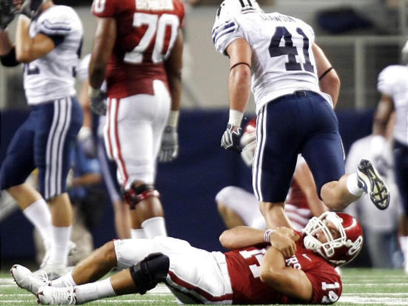 Oklahoma QB Sam Bradford rolls over in pain after being hit and dropped by BYU's Coleby Clawson late in the second quarter Saturday.