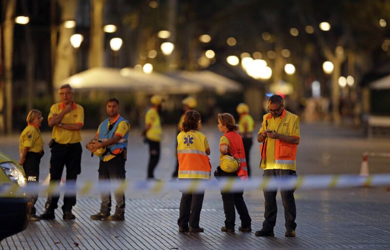 FILE - Emergency workers stand on a blocked street in Barcelona, Spain, Thursday, Aug. 17, 2017. The lone fugitive from the Spanish cell that killed 15 people in and near Barcelona was shot to death Monday after he flashed what turned out to be a fake sui