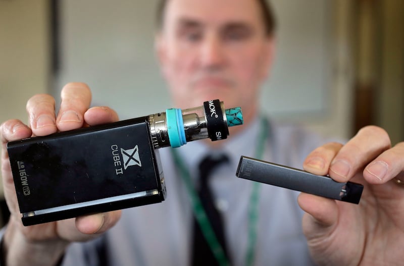 In this Tuesday, April 10, 2018, photo Marshfield High School Principal Robert Keuther displays vaping devices that were confiscated from students in such places as restrooms or hallways at the school in Marshfield, Mass. Health and education officials ac