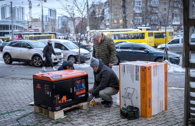 Ukrainians unpack a power generator before installing it at a bank branch in Kyiv, Ukraine, on Thursday, Dec. 1, 2022.