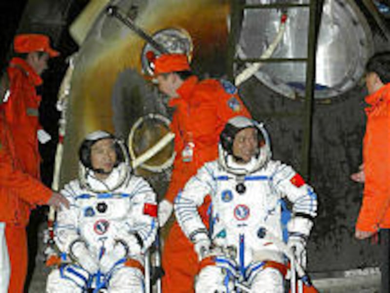 Astronauts Fei Junlong, left, and Nie Haisheng sit beside the re-entry capsule of China's second manned spacecraft, Shenzhou 6, after landing in Siziwang Banner County.