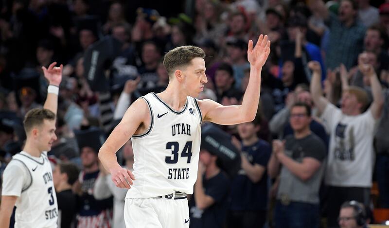 Utah State guard Steven Ashworth and forward Justin Bean, wearing white, wave to the crowd