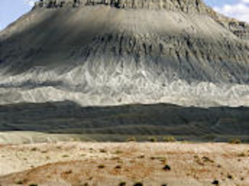 ATV tracks cross the land leading to Factory Butte, rear, northwest of Caineville, Utah. For off-roaders, few places are as good as the badlands at Factory Butte.