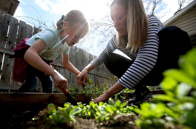Isla Morley and her mother Sharri Morley pull weeds from a garden box outside their home in Salt Lake City on Friday, April 20, 2018.