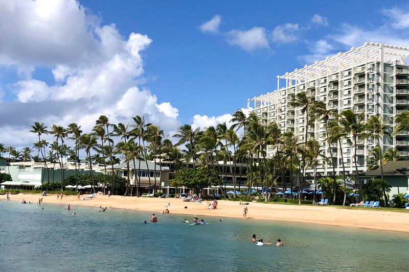 People are seen on the beach of the Kahala Hotel & Resort in Honolulu.