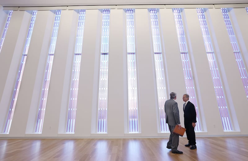 Two men walk near the stained glass windows in a new chapel.
