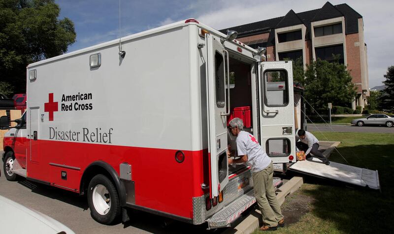 Red Cross workers load a Red Cross vehicle with supplies.