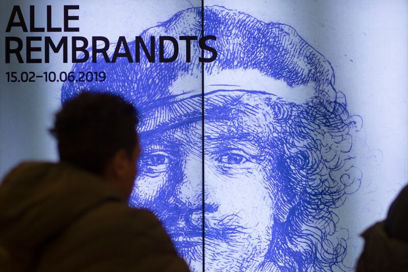 A visitor passes a billboard drawing attention to the exhibit of all the Rijksmuseum’s Rembrandts in Amsterdam, Netherlands.