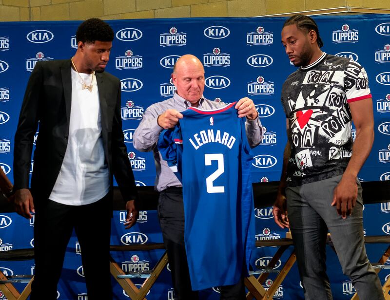 Los Angeles Clippers team chairman Steve Ballmer, center, presents a new team jersey to Kawhi Leonard, right, as Paul George looks on during a press conference in Los Angeles, Wednesday, July 24, 2019. Nearly three weeks after the native Southern Californ