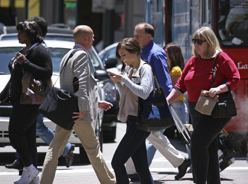 In this photo taken Wednesday, June, 29, 2010, a woman text messages while walking across the street in San Francisco.
