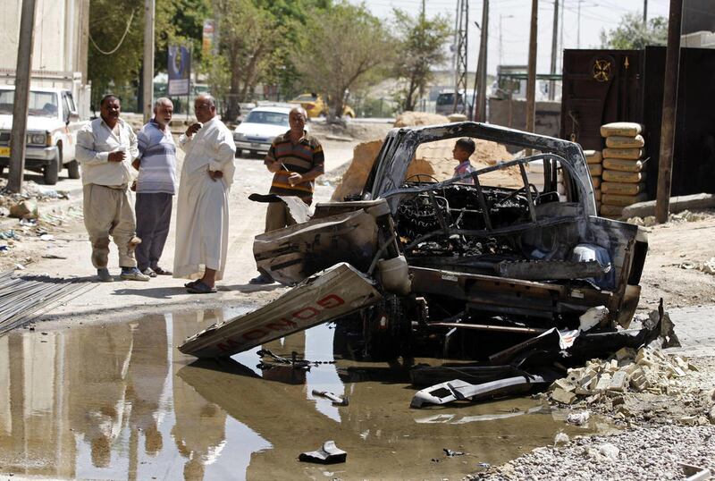 Civilians inspect the aftermath of a car bomb attack in Baghdad, Iraq, Wednesday, July 24, 2013. A bomb exploded near a Sunni mosque in Baghdad's southern Dora neighborhood on Tuesday, killing several people and wounding many more, police said. (AP Photo