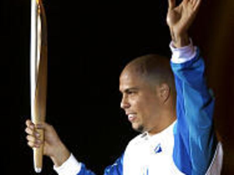 Brazilian soccer star Ronaldo waves as he holds the Olympic Torch in Rio de Janeiro.