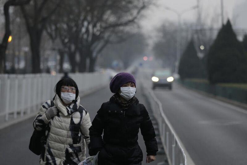Women wear masks as they walk along a street on a polluted day in Beijing, Sunday, Dec. 13, 2015.