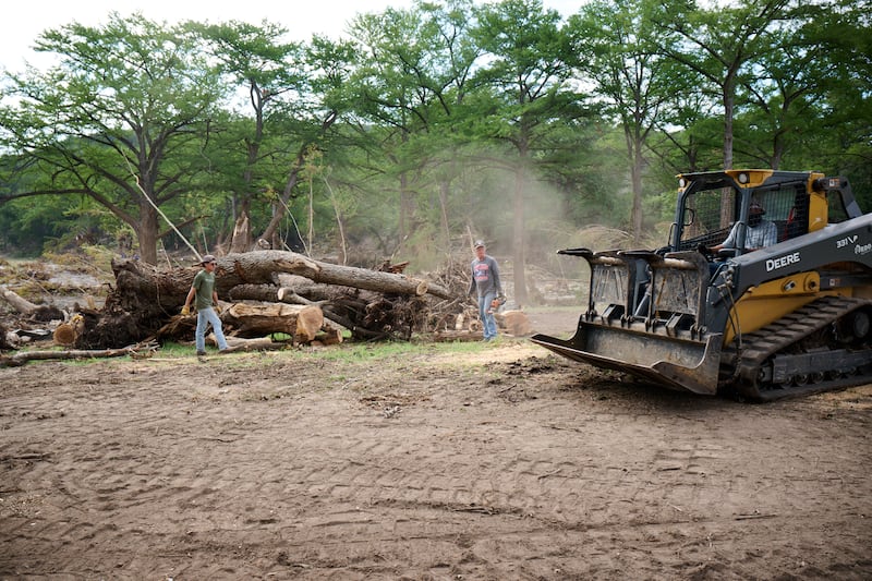 Volunteers from the Cypress Creek Church in Wimberley, Texas, remove downed trees from the Guadalupe River in Hunt, Texas, on July 26, 2025, following the severe flooding that hit central Texas on July 4, 2025.