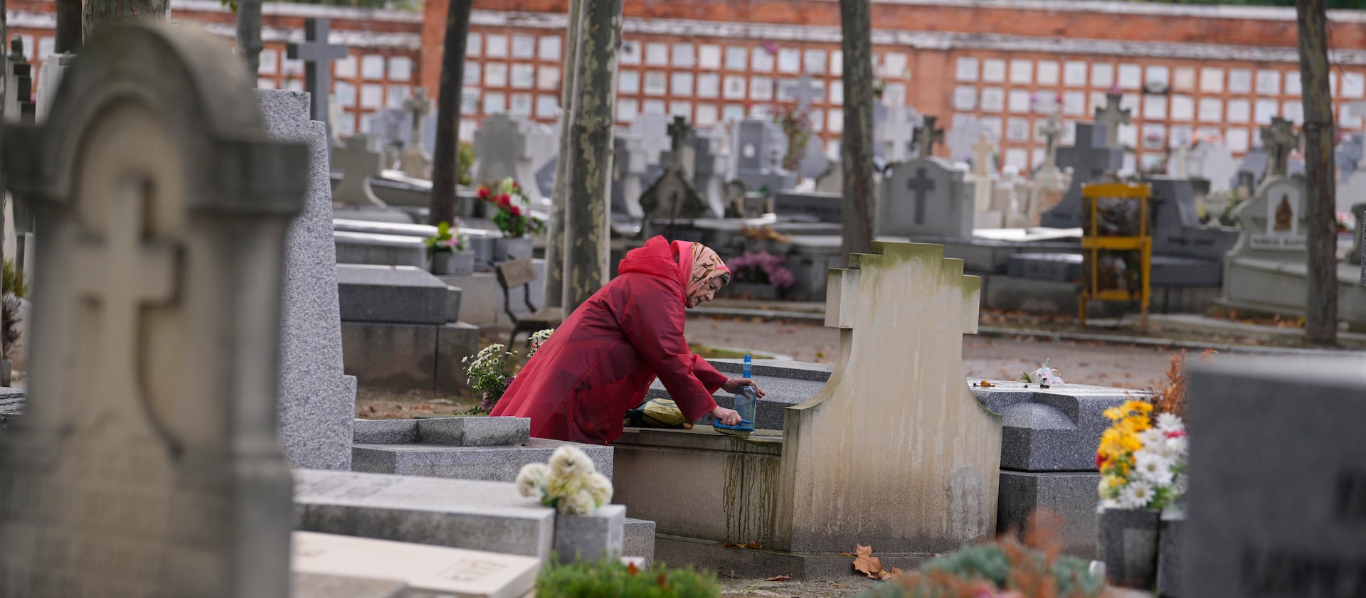 A woman cleans a relative’s tombstone in the Almudena cemetery a day before All Saints Day in Madrid, Spain.