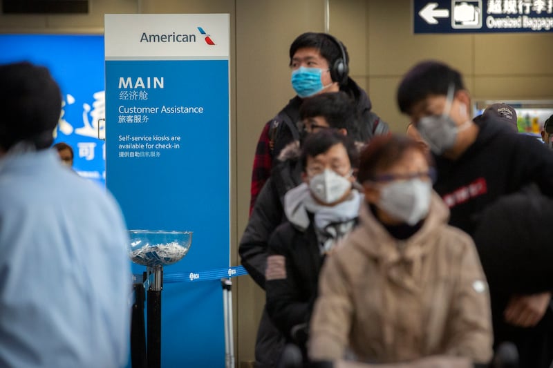 Travelers wearing face masks line up to check in for an American Airlines flight to Los Angeles at Beijing Capital International Airport in Beijing, Thursday, Jan. 30, 2020. China counted 170 deaths from a new virus Thursday and more countries reported infections, including some spread locally, as foreign evacuees from China’s worst-hit region returned home to medical observation and even isolation. (AP Photo/Mark Schiefelbein)