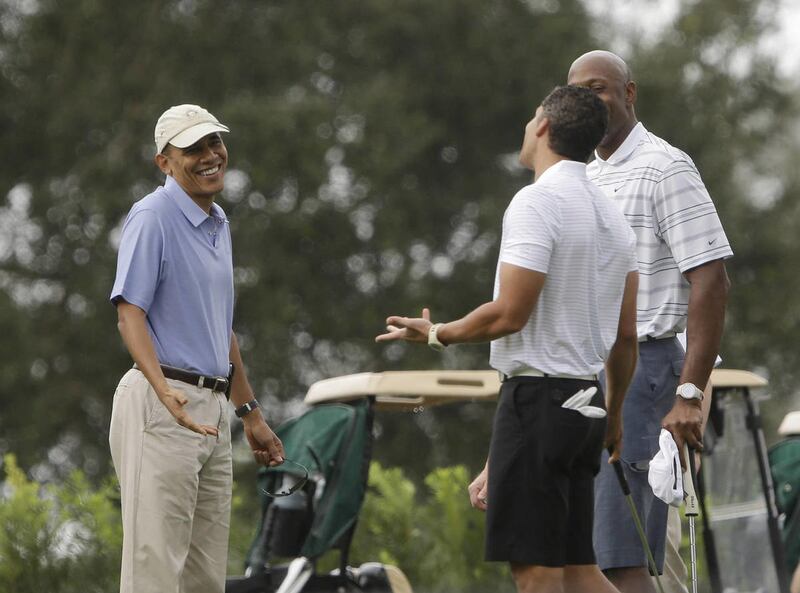 President Barack Obama, left, shrugs his shoulders as he talks with former NBA basketball player Alonzo Mourning, right, and Cyrus Walker, the cousin of senior presidential adviser Valerie Jarrett, at Grande Oaks golf club, Saturday, Nov. 9, 2013 in Ft.