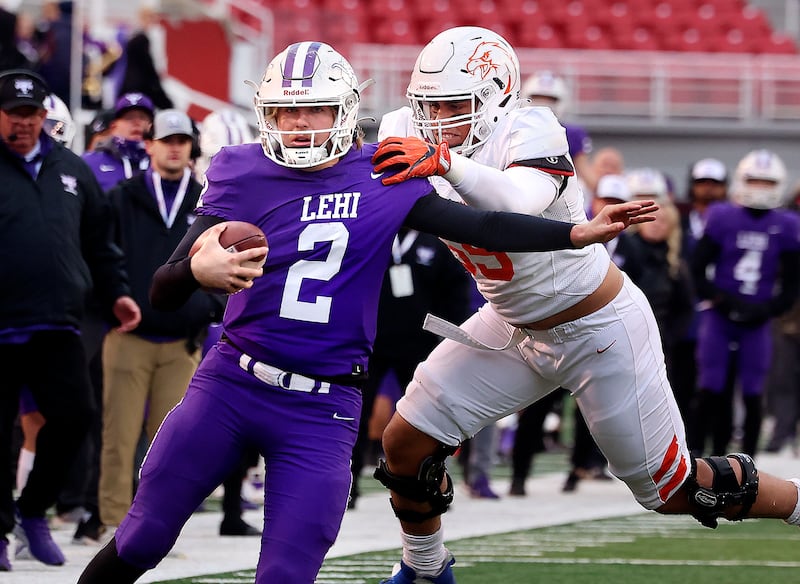 Lehi’s QB Jackson Brousseau, wearing purple, runs the ball past Timpview’s Spencer Fano