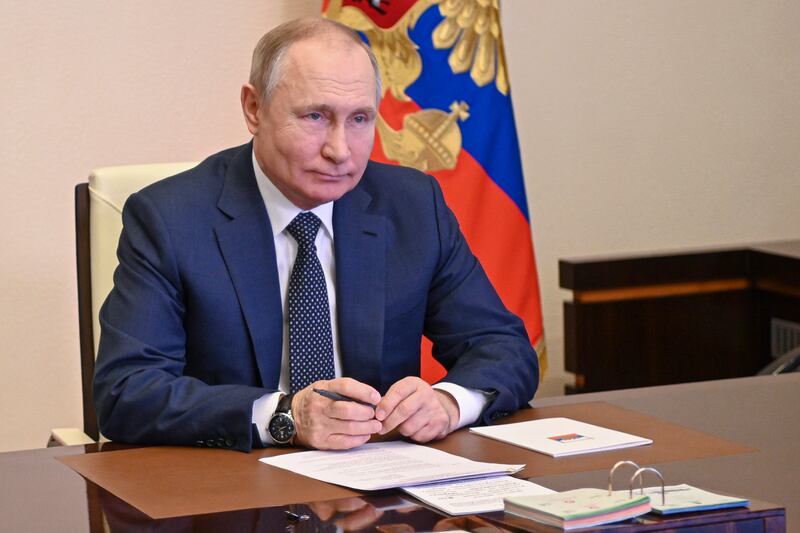 Russian President Vladimir Putin sits at a desk.