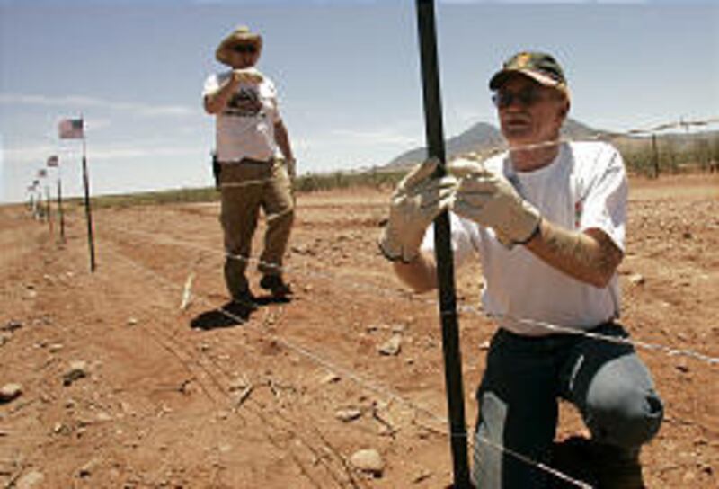 Minutemen volunteers Jack Pate, left, and Sam Wright help build a security fence along the border near Palominas, Ariz., Saturday. The first step is a 10-mile fence.