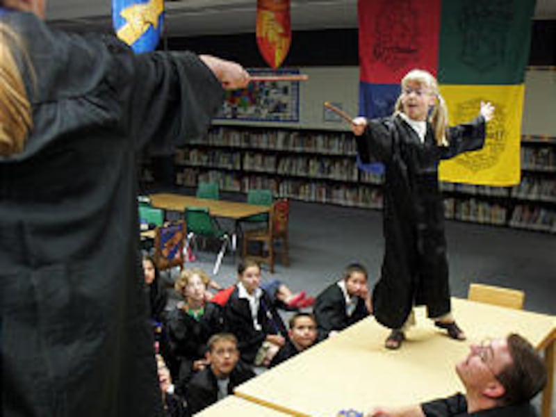 Hemmy Visick, 9, of Logan uses her wand to "duel" with Amy Bradfield, 11, of Star Valley, Wyo., during a Hogwarts Academy summer program at Hillcrest Elementary in Logan. Watching the duel is teacher Reed Olson.