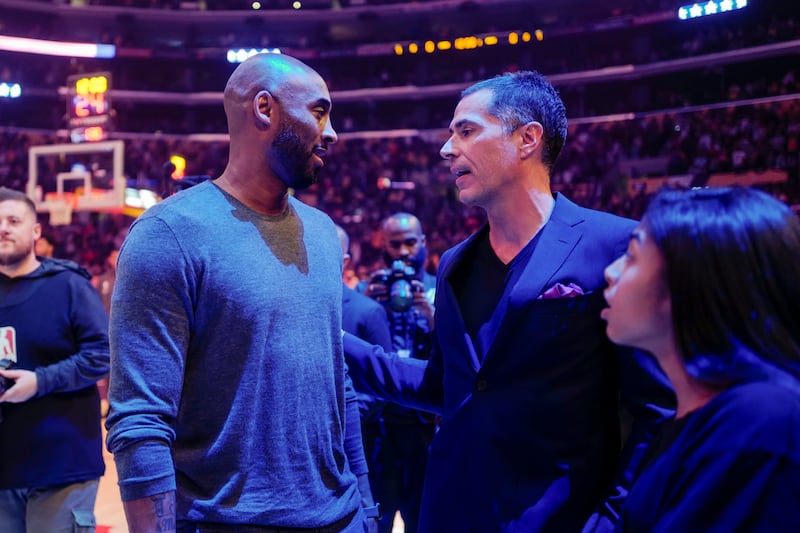 Former Los Angeles Lakers Kobe Bryant talks with Rob Pelinka during an NBA basketball game between Los Angeles Lakers and Atlanta Hawks, Sunday, Nov. 17, 2019, in Los Angeles. The Lakers won 122-101. (AP Photo/Ringo H.W. Chiu)
