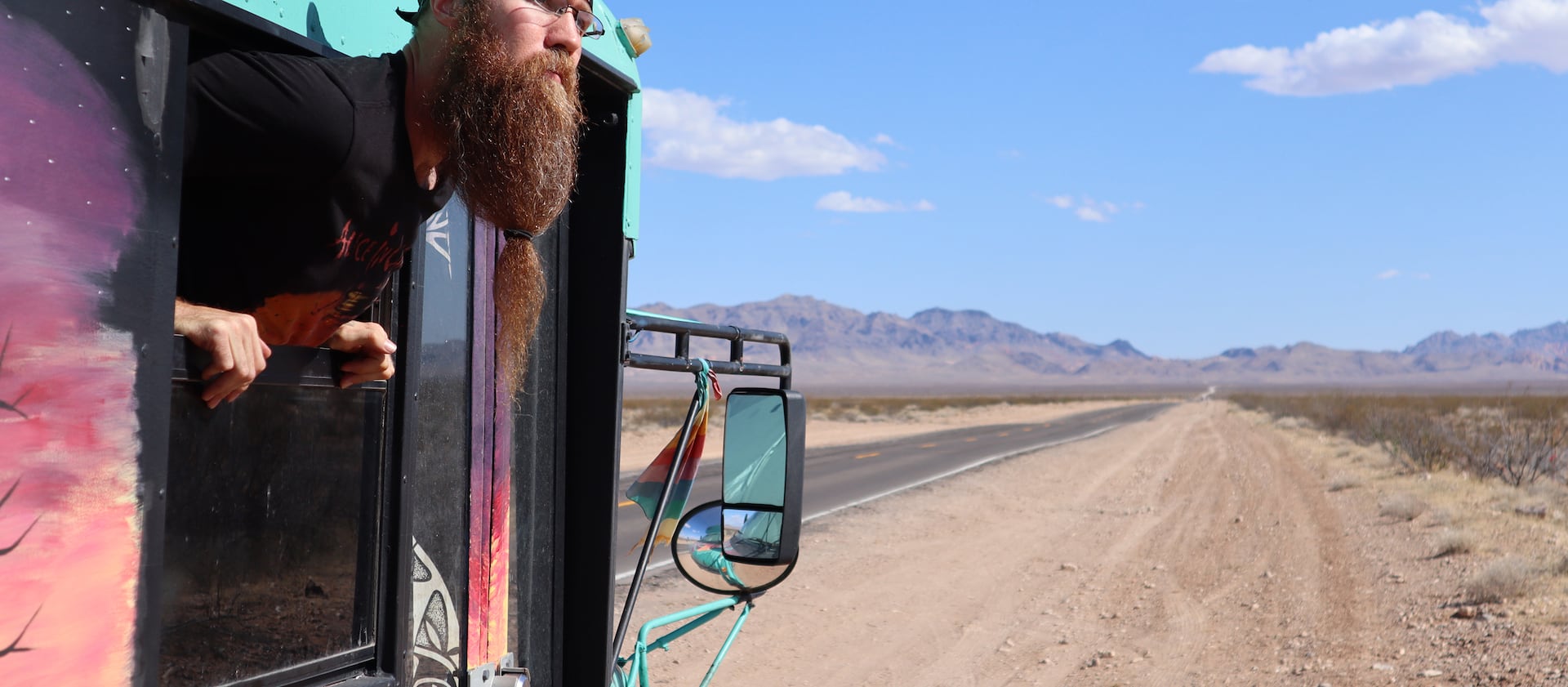 Luke Brokaw looks out the window of the converted school bus that he lives in while working remotely.
